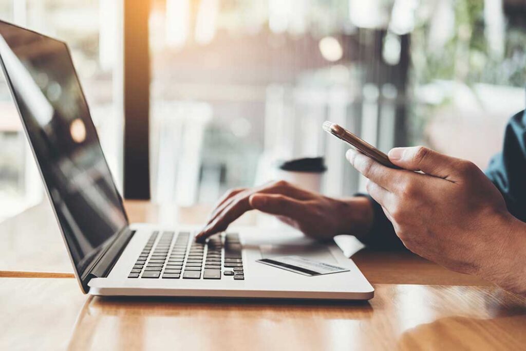 An adult reviews retirement savings paperwork at a kitchen table, calculator and laptop nearby.